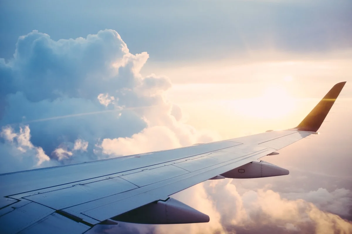 Airplane wing over clouds at golden hour — European summer aviation
